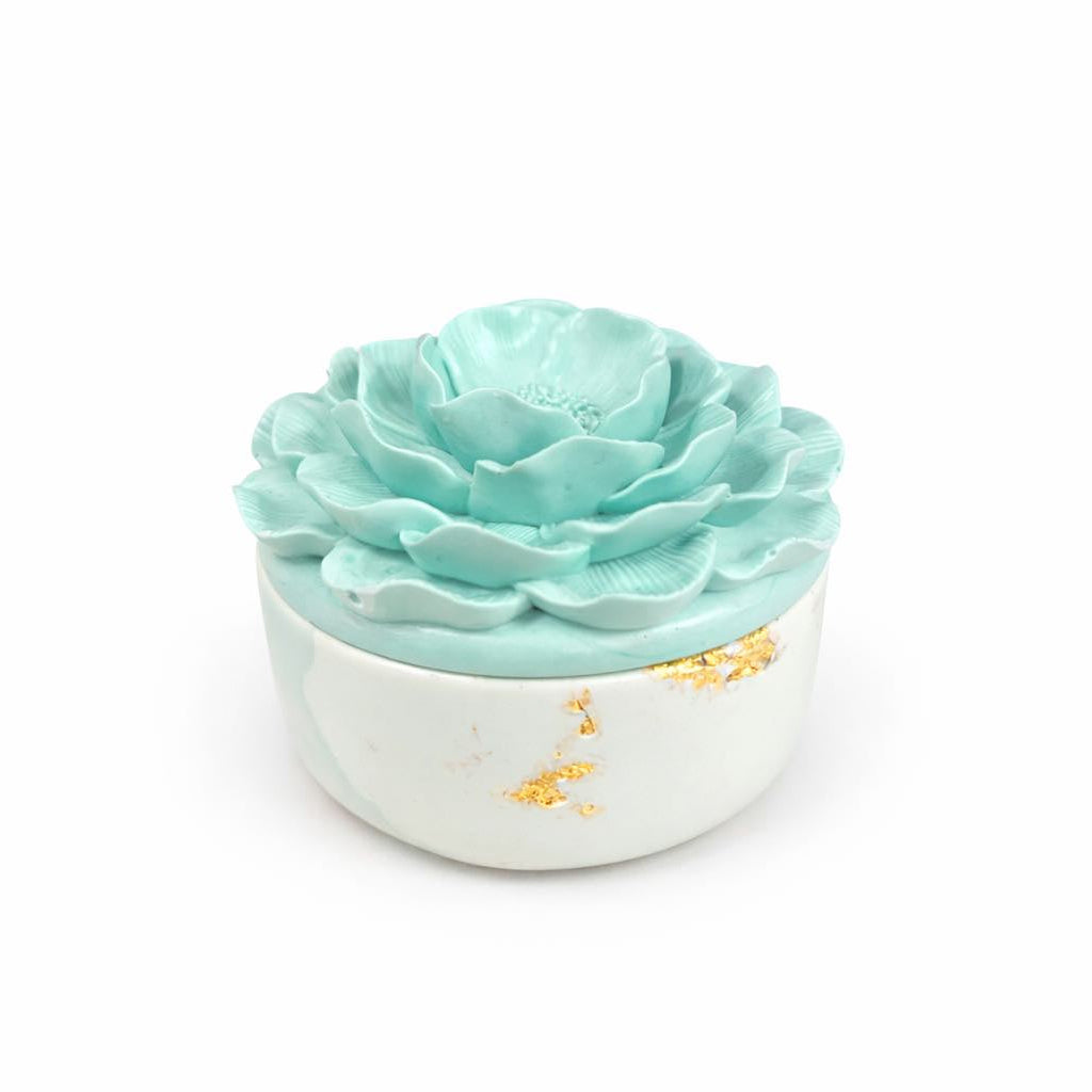 Mint green rose-shaped soap in a white container with gold accents on a white background