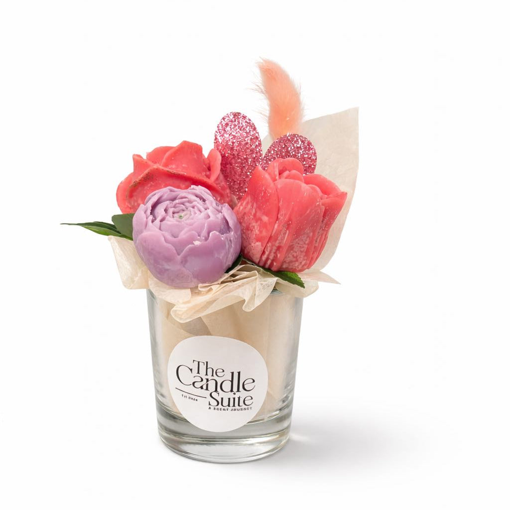 Decorative candle with flowers in a glass holder on a white background, branded 'The Candle Suite'.