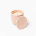 Pink candle in a matching container with lid on a white background