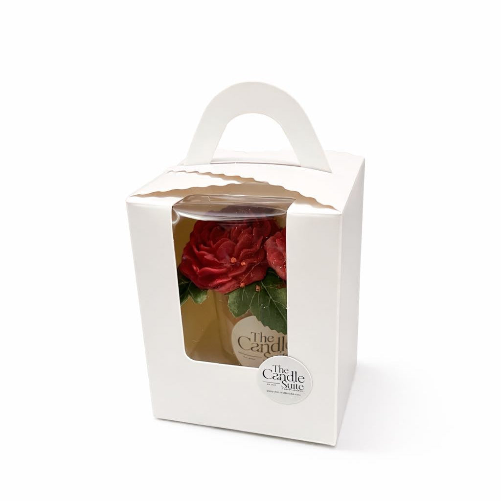 Candle in a white box with a red rose design on a white background