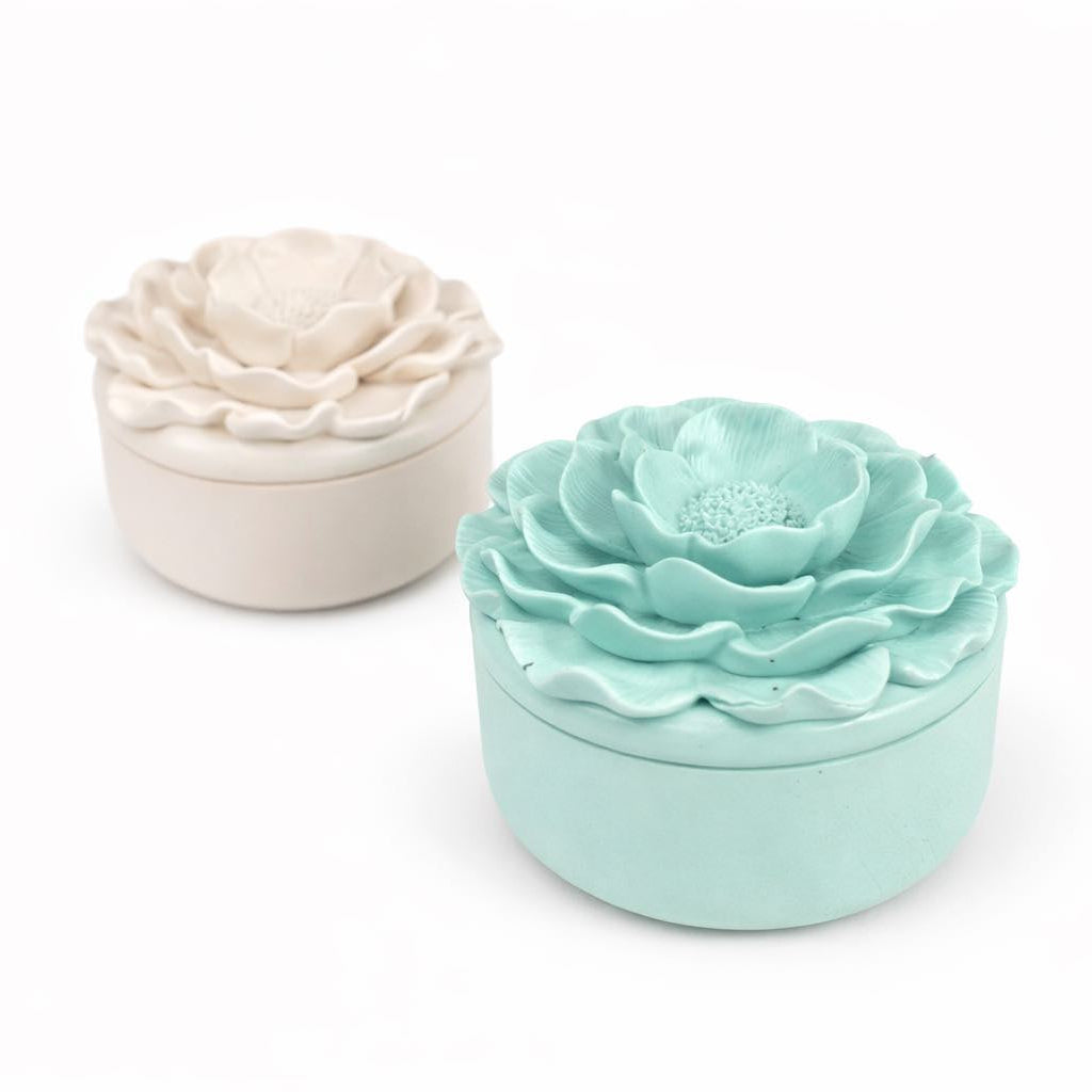 Two floral-shaped bath bombs, one white and one light blue, on a white background.