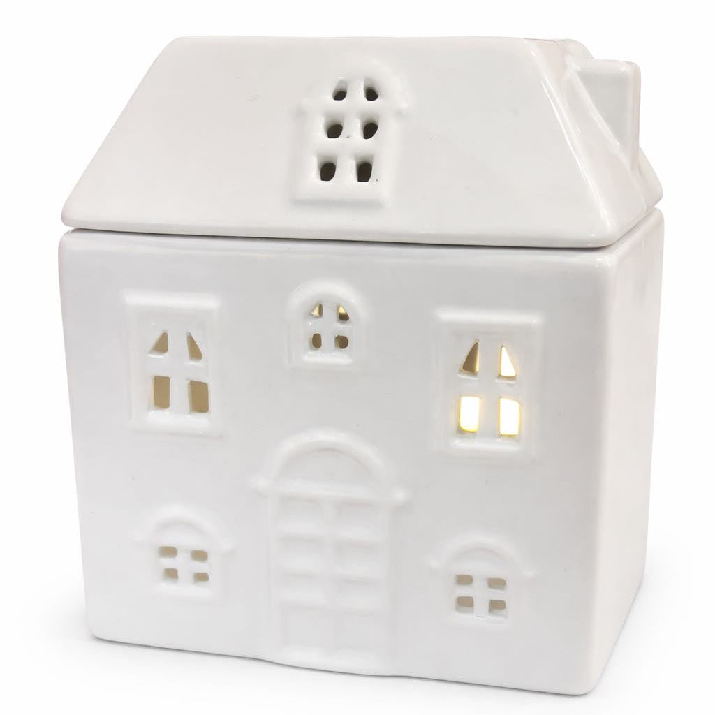 White ceramic house-shaped wax burner with small lights inside on a white background