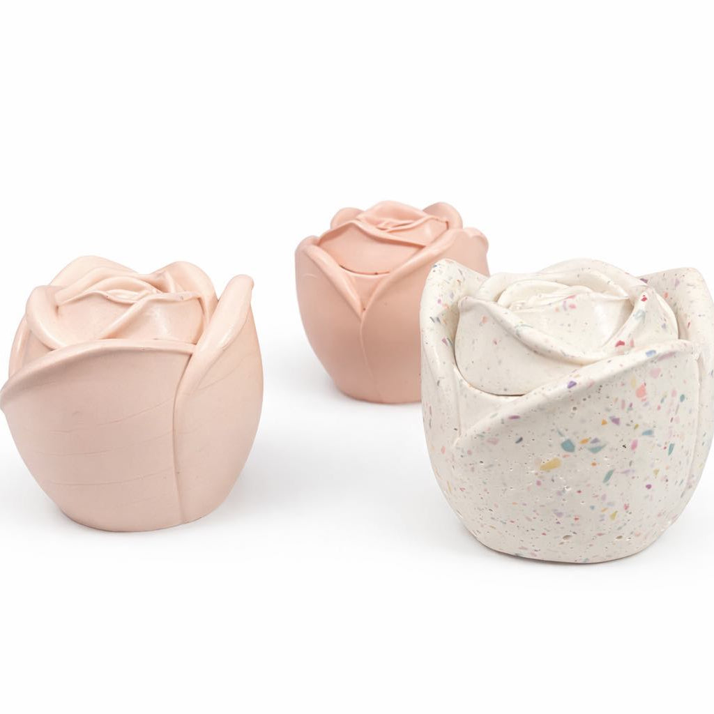 Three tulip-shaped candles in pink and beige on a white background