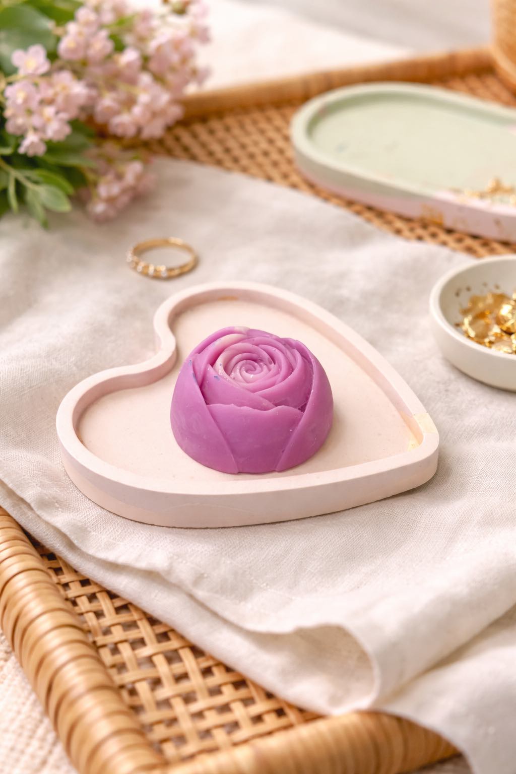 Heart-shaped dish with a purple rose-shaped soap on a light fabric background