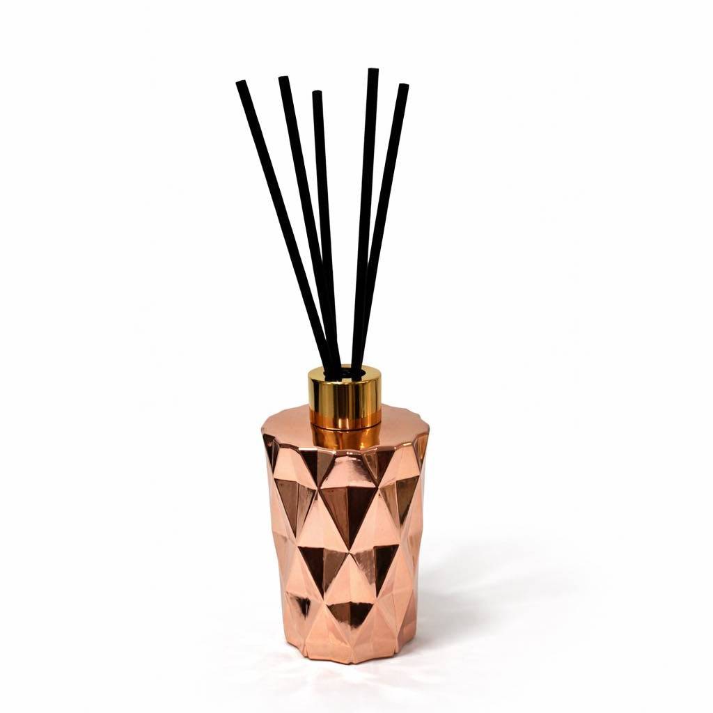 Copper diffuser with black sticks on a white background