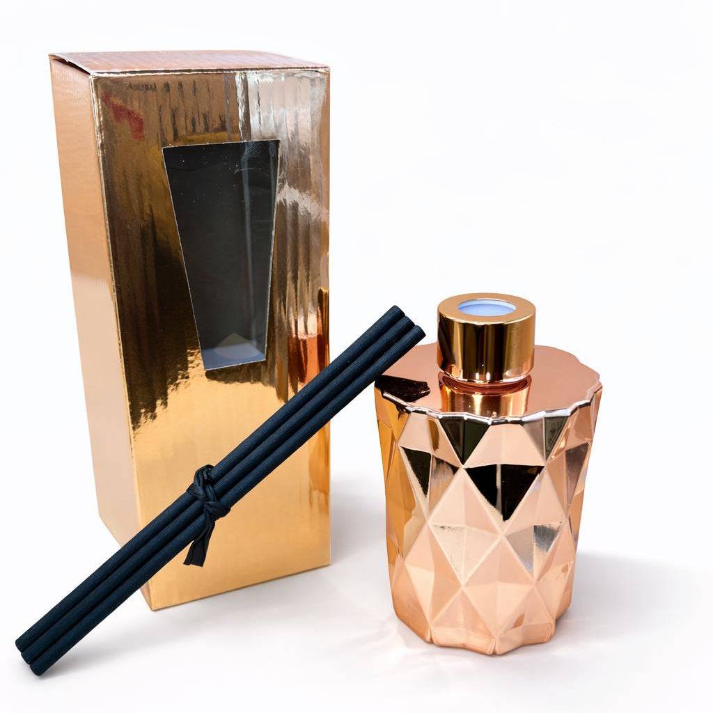 Rose gold geometric diffuser with black reeds and packaging on a white background