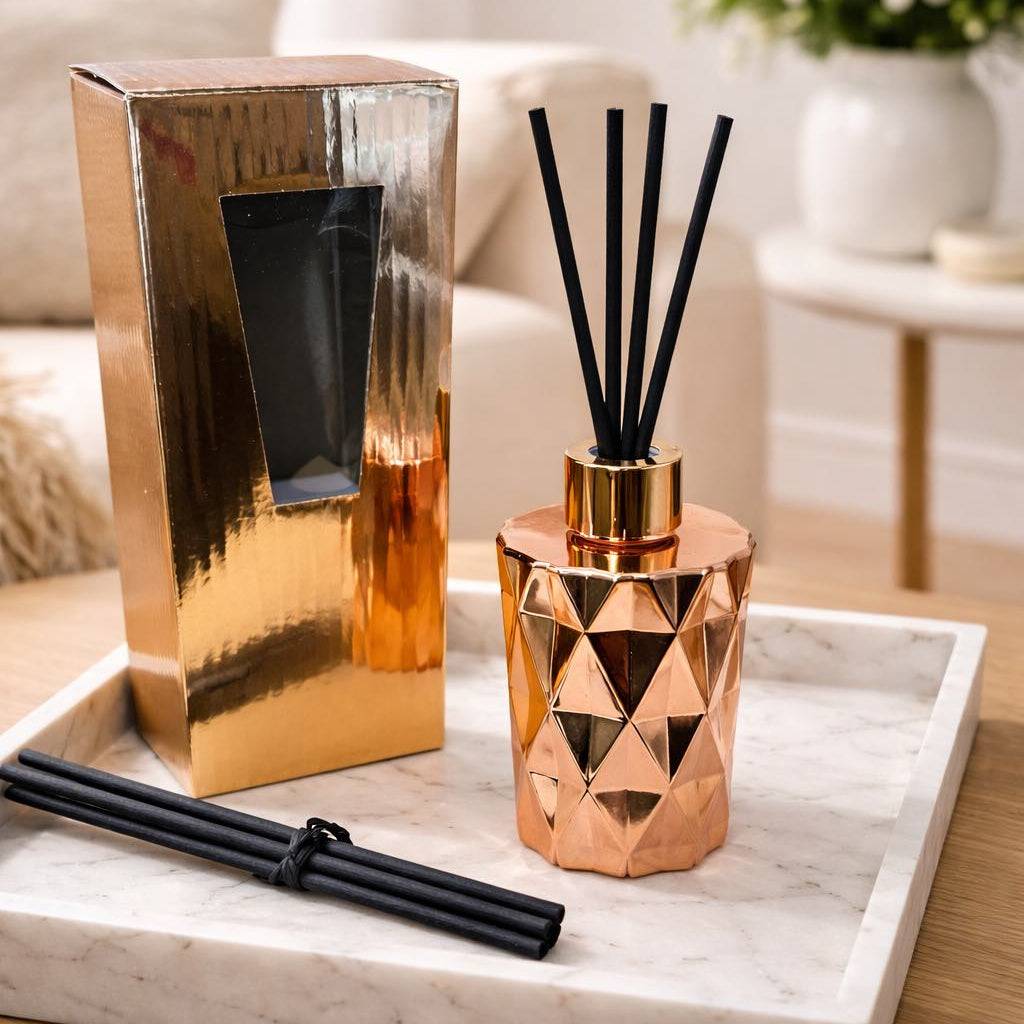 Rose gold diffuser with black reeds on a marble tray in a living room setting