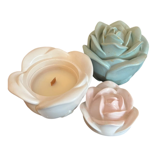 Three rose-shaped candles in different colors on a white background