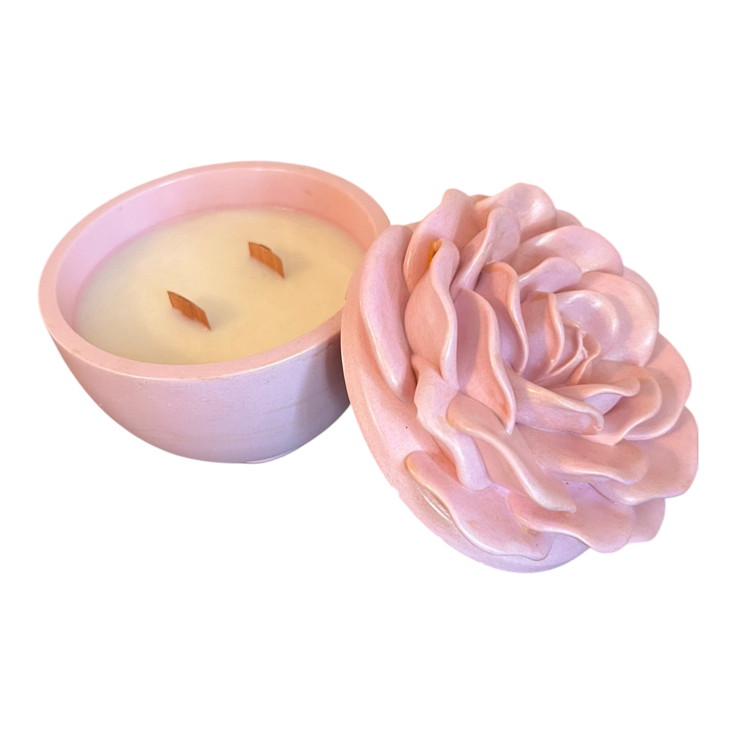 Pink rose-shaped candle next to a small pink candle holder with a lit candle inside on a white background