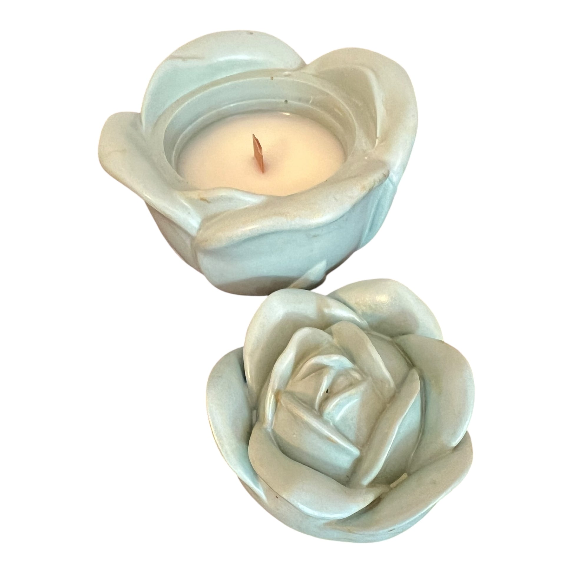 Two ceramic rose-shaped candle holders with a lit candle inside on a white background