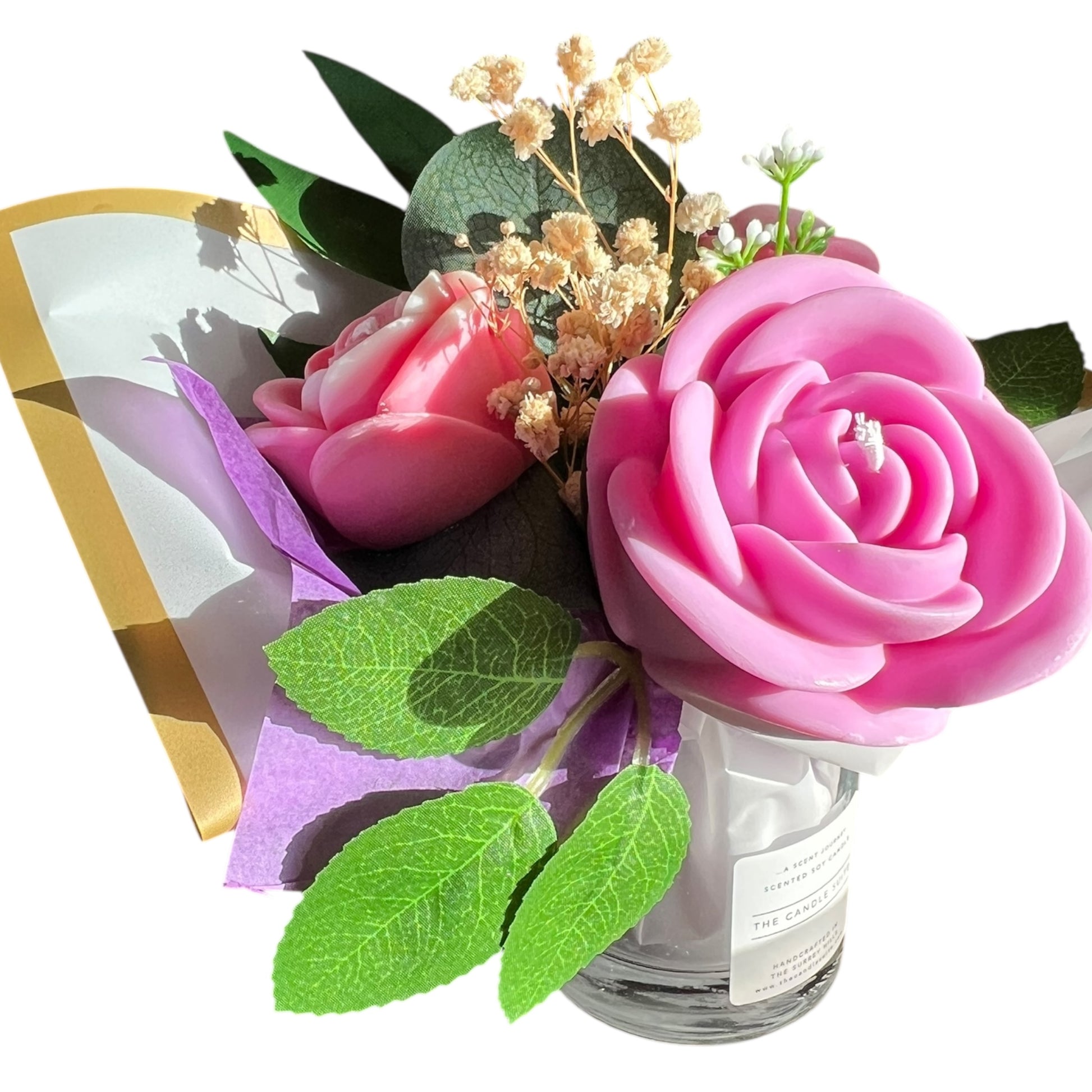 Bouquet of pink rose-shaped candles with green leaves on a white background